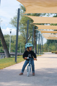 Kilkuletnia dziewczynka na rowerze. Na głowie ma niebieski kask