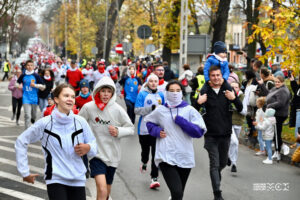 Grupa osób w różnym wieku biegnąca ulicą