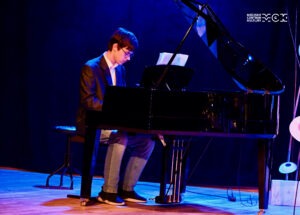 Nastoletni chłopak gra na fortepianie.