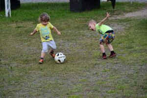 Dwóch małych chłopców kopiących piłkę.
