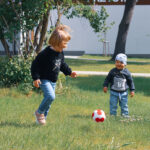Małe dzieci grają na trawniku w piłkę.