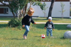 Małe dzieci grają na trawniku w piłkę.