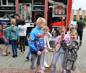 Grupa dzieci stoi przy samochodzie strażackim