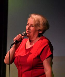 Kobieta w wieku senioralnym śpiewa do milrofonu