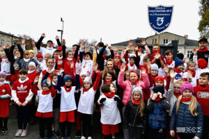 Grupa kuiludziesięciu dzieci ubranych w białe lub czerwone koszulki. Część z nich ma podniesione ręce w geście radości.