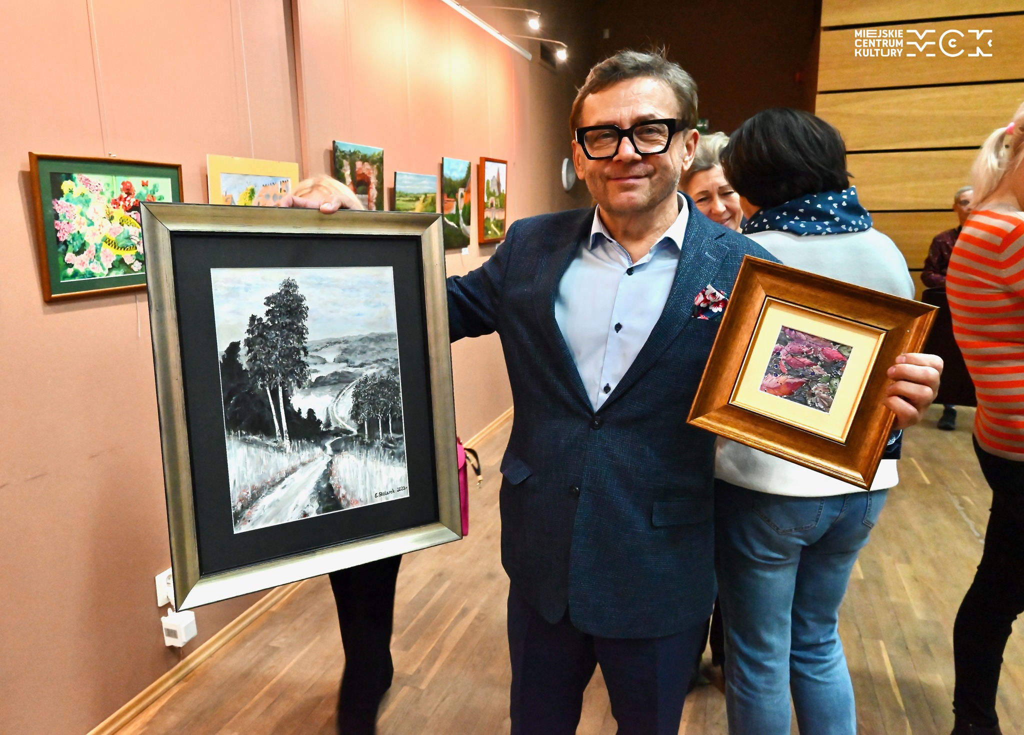 Mężczyzna trzymający w obu rękach obrazy.