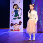 Mała dziewczynka śpiewa na scenie.