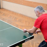 Zdjęcie przedstawia mężczyznę w trakcie gry w tenisa stołowego.