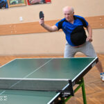 Zdjęcie przedstawia mężczyznę w trakcie gry w tenisa stołowego.
