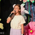 Młoda dziewczynka śpiewa na scenie.